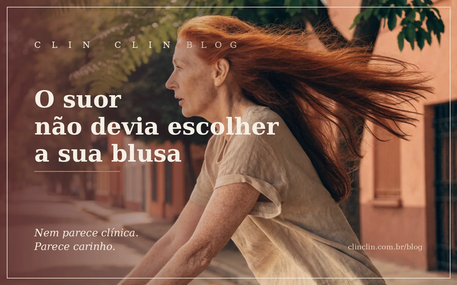 Mulher branca de cabelo ruivo longo e liso, por volta dos cinquenta anos, pedalando de bicicleta por uma rua arborizada no fim da tarde, de camiseta de manga curta, o vento no cabelo e o rosto concentrado no caminho.