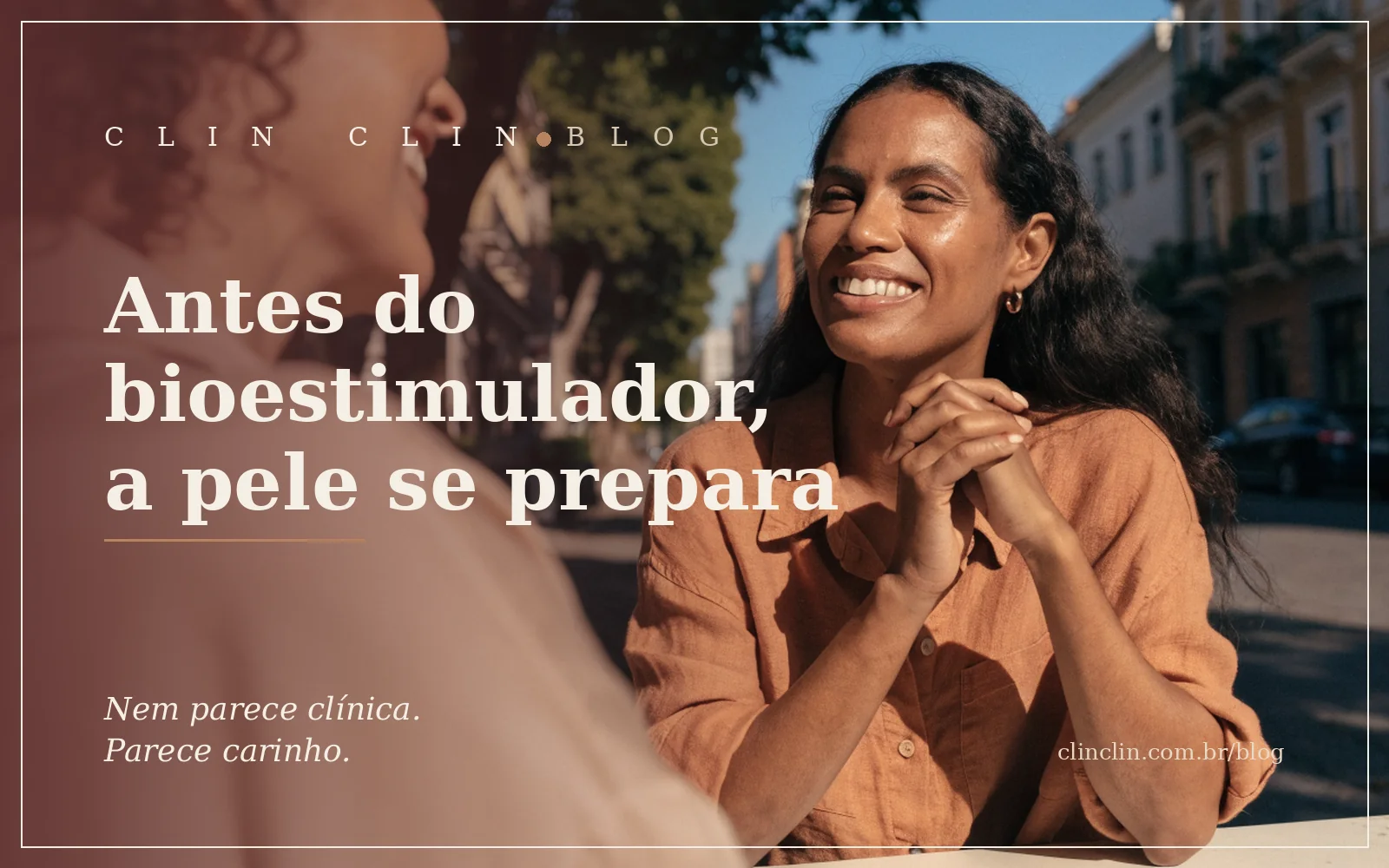 Mulher de uns trinta anos, pele morena e cabelo longo escuro solto, sorrindo de mãos juntas numa mesa de café na calçada, em conversa animada com uma amiga, na luz dourada do fim de tarde.