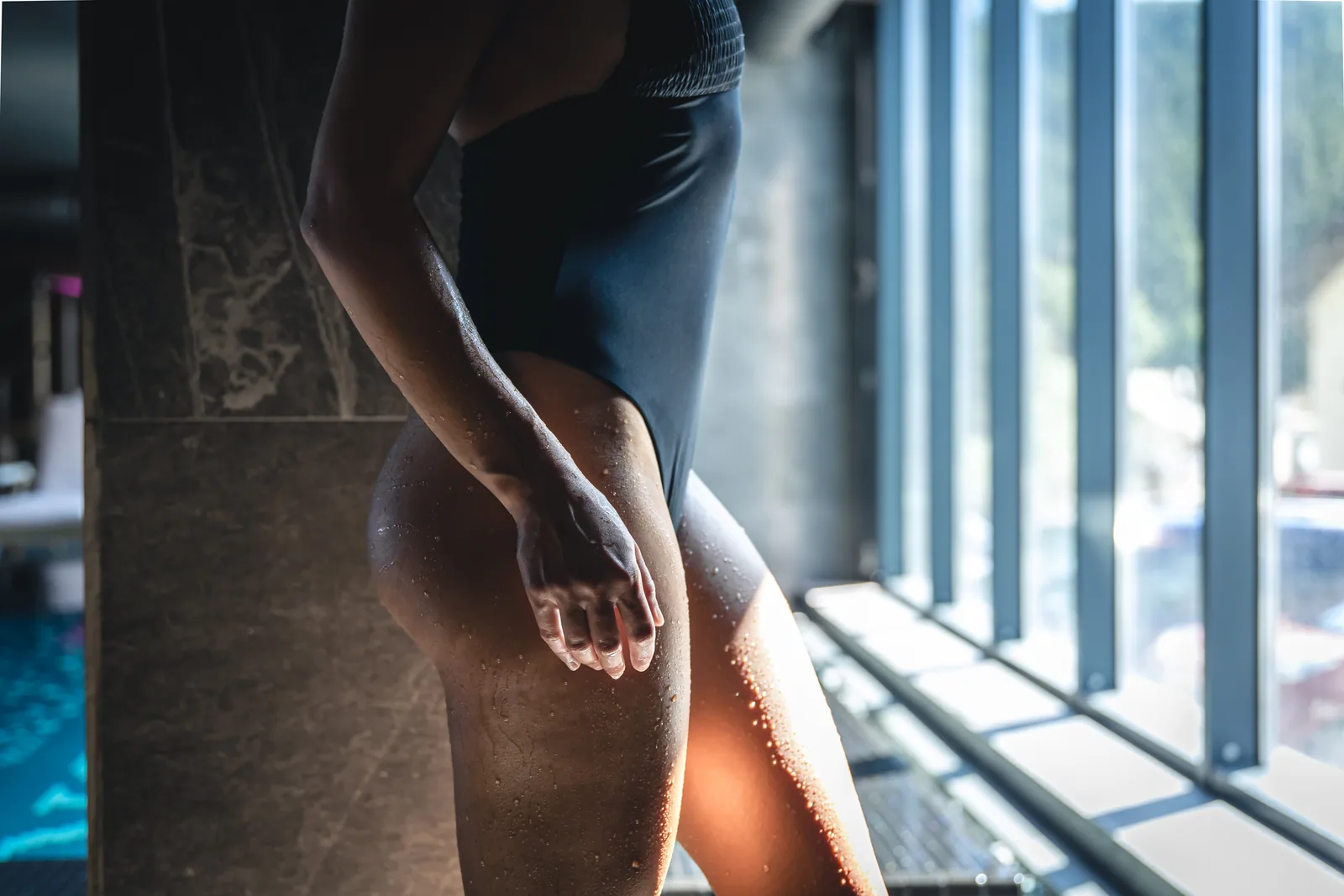 Mulher em maiô, relaxada perto da piscina de um spa