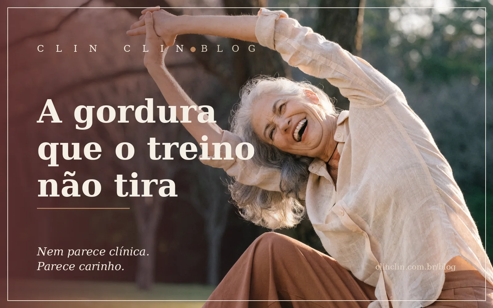 Mulher branca, perto dos sessenta anos, cabelo grisalho solto ao vento, alongando os braços acima da cabeça e rindo alto, sentada num gramado de parque na luz dourada da manhã, calça terracota e camisa bege.